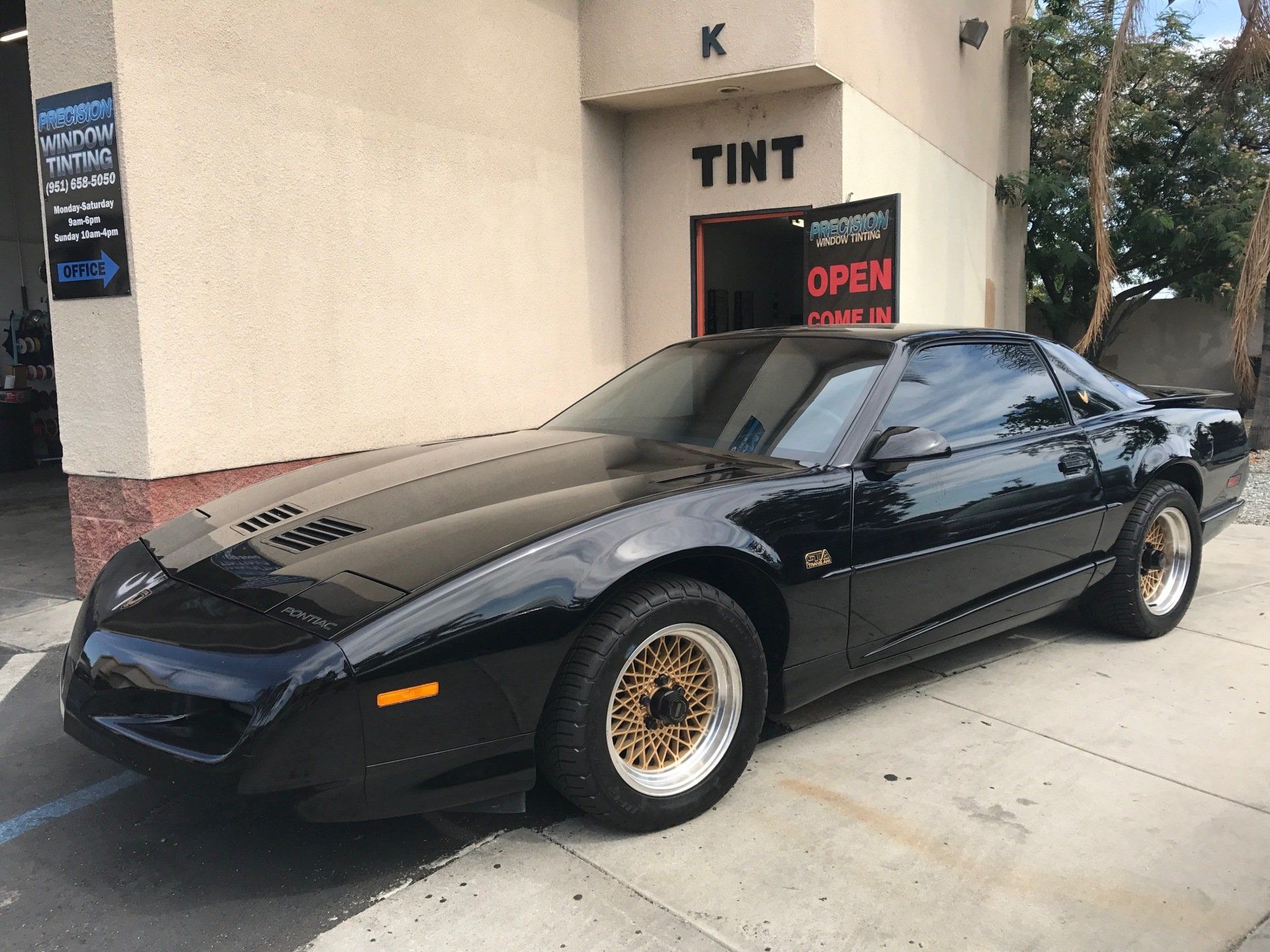 A black car is parked in front of a tint shop