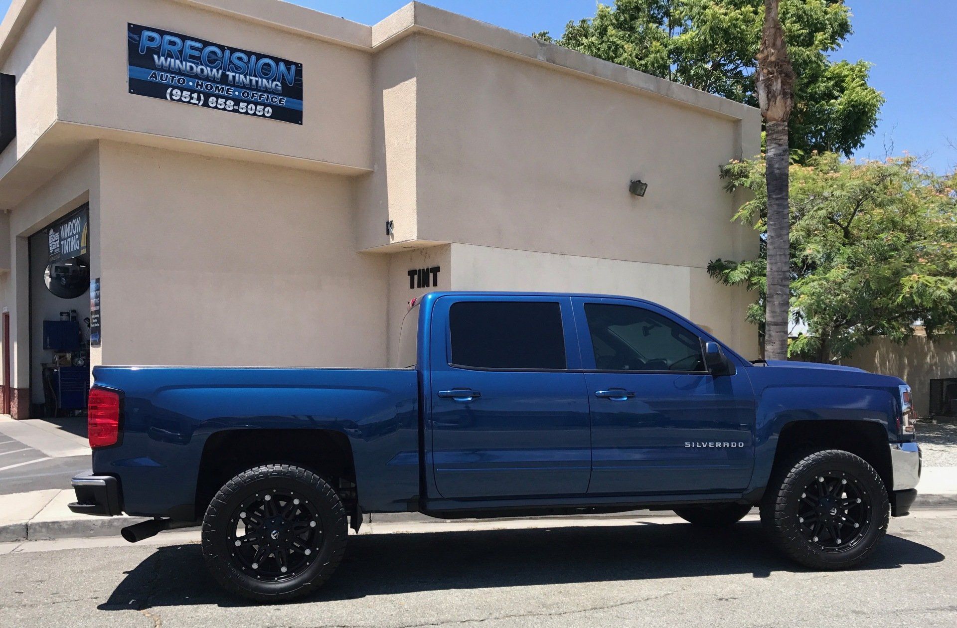 A blue truck is parked in front of a building that says Precision