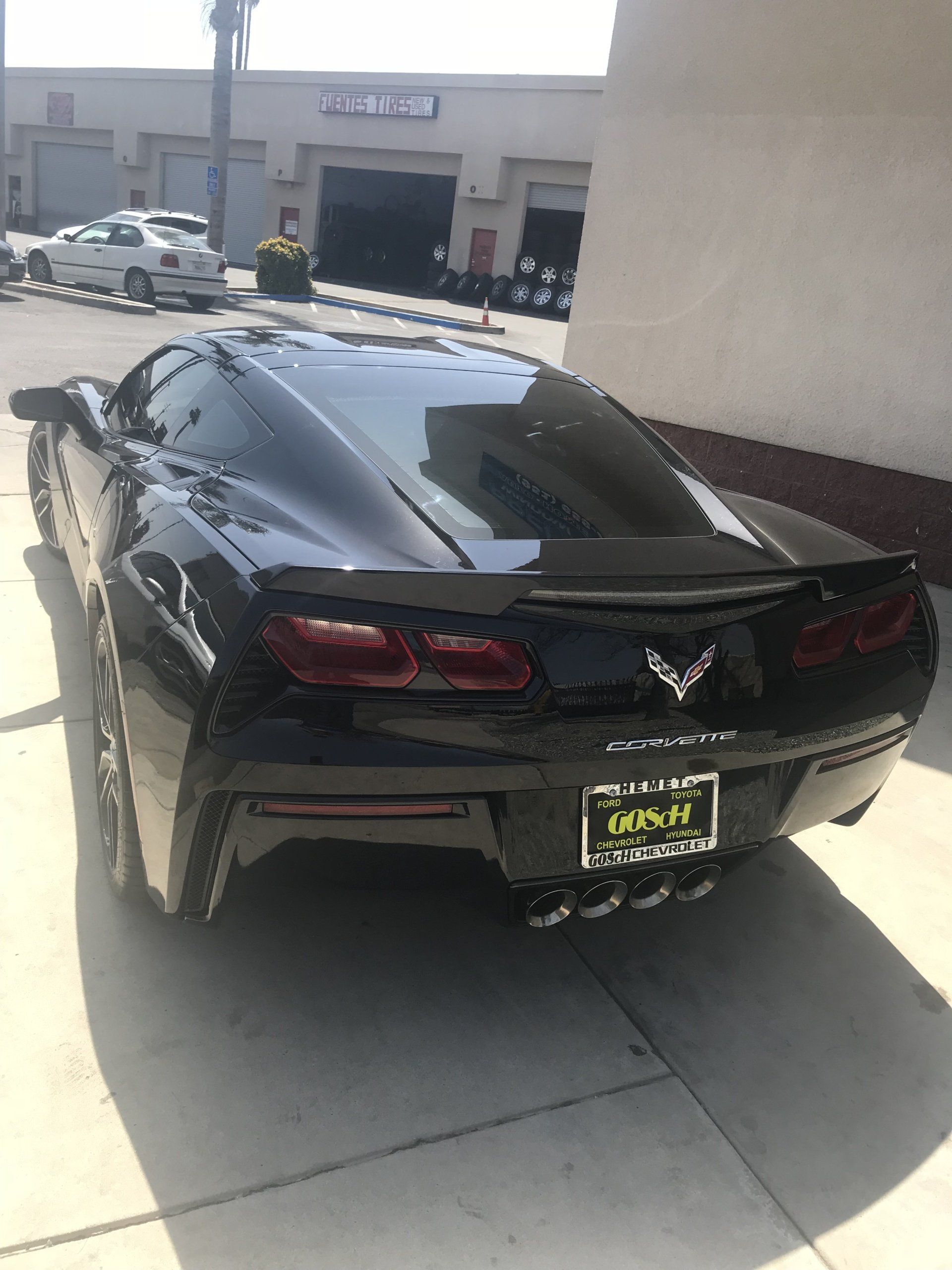 A black sports car is parked on the sidewalk in front of a building