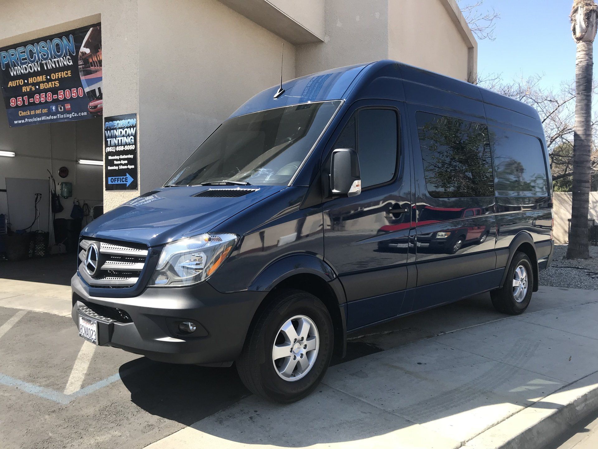A blue van is parked on the side of the road in front of a building