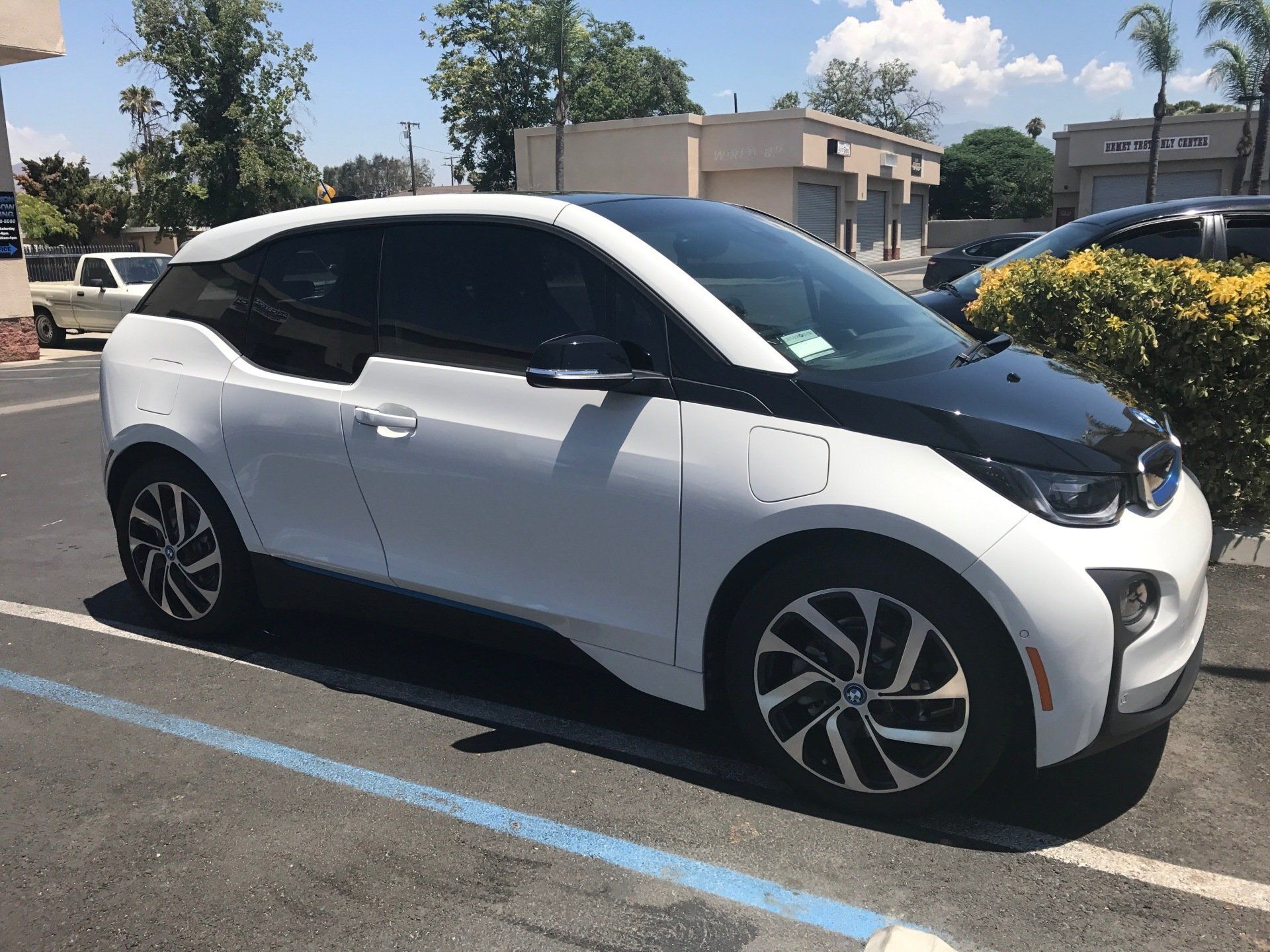 A white BMW i3 is parked in a parking lot