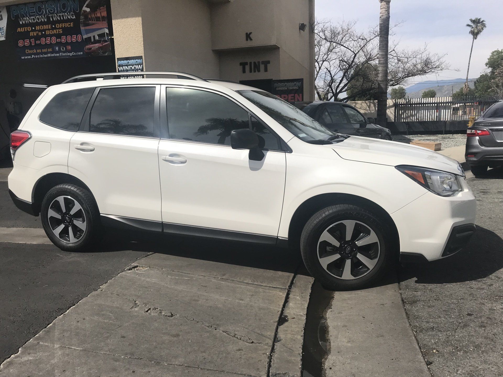 A white suv is parked on the side of the road in front of a building