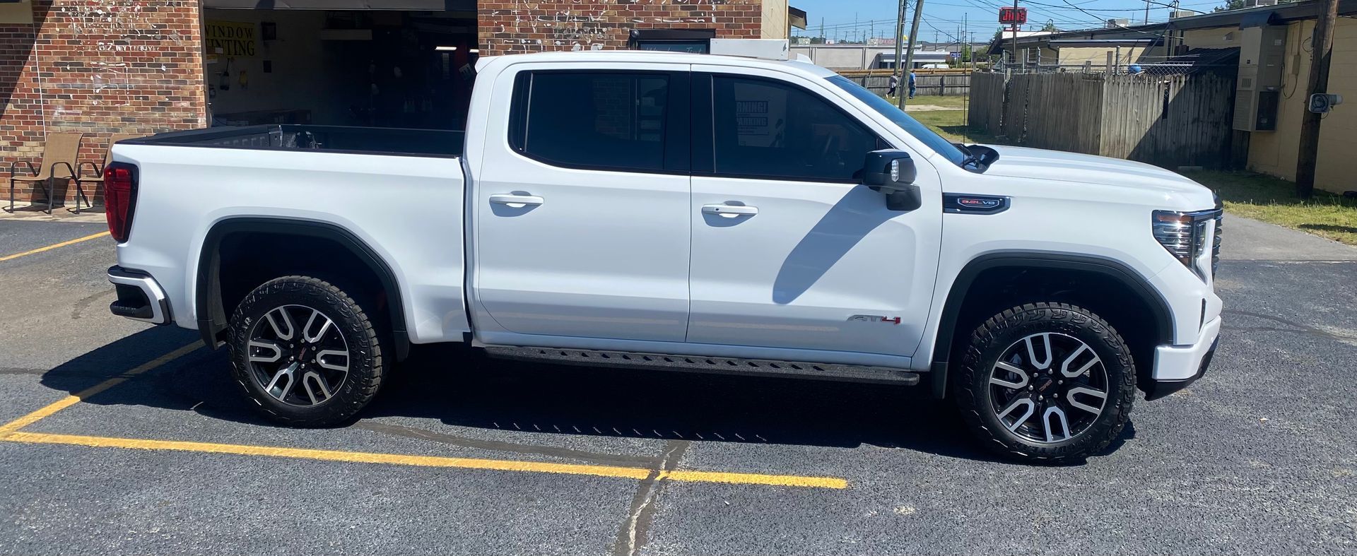 A white truck is parked in a parking lot in front of a building.