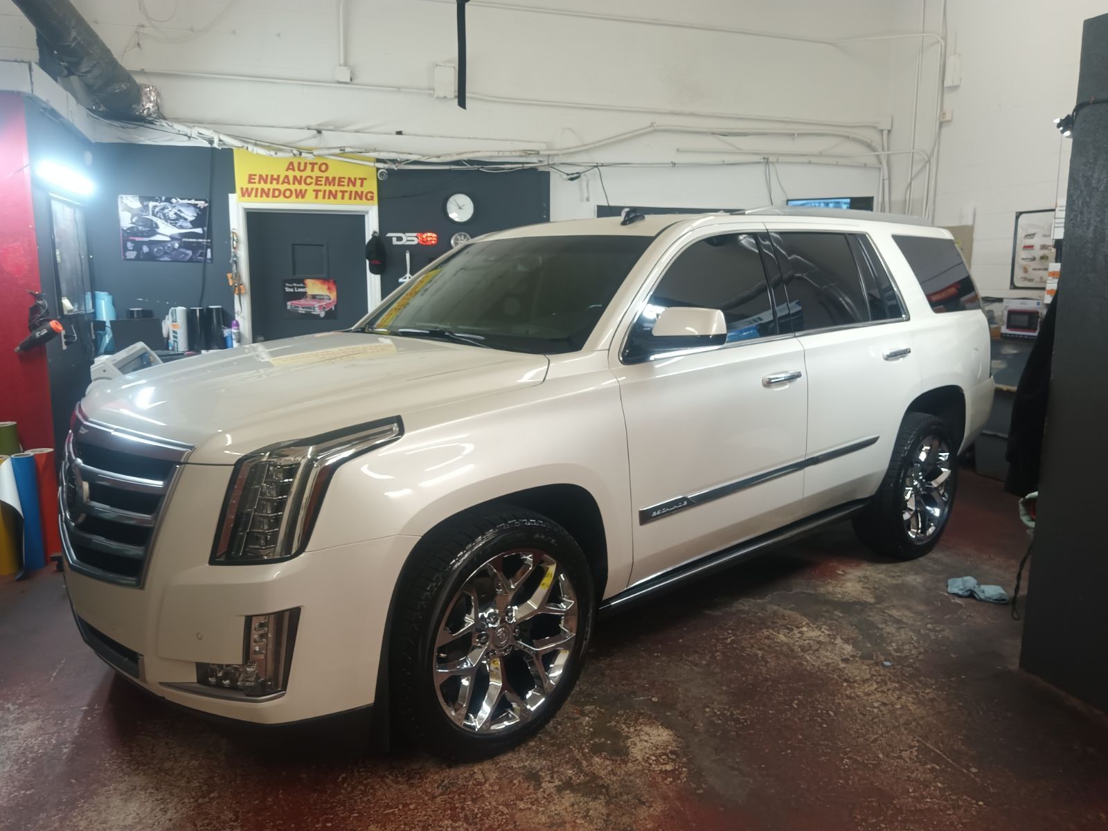 A white cadillac escalade is parked in a garage.