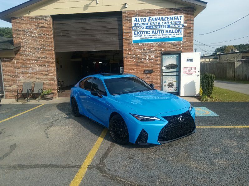 A blue car is parked in front of a brick building.