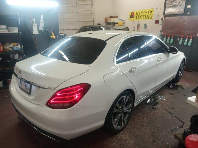 A white mercedes benz c class is parked in a garage.