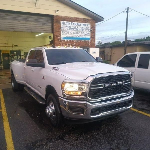 A white ram truck is parked in a parking lot in front of a garage.