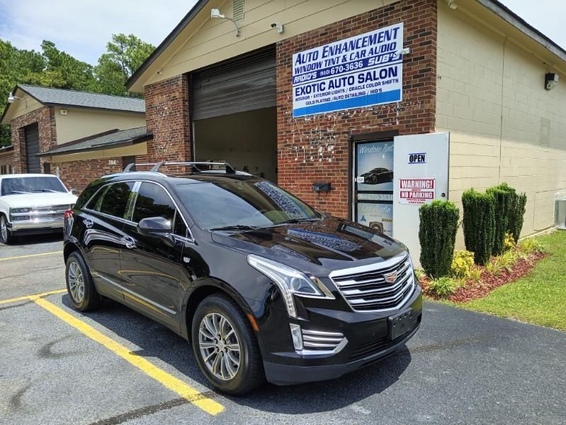 A black car is parked in front of a brick building.