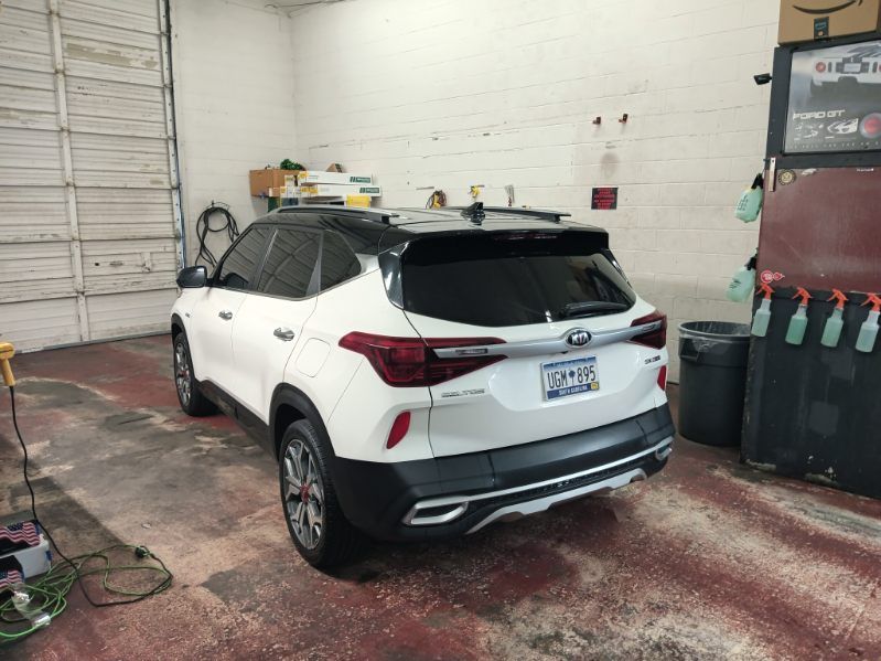 A white car is parked in a garage next to a wall.