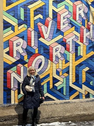 Person standing in front of a colorful geometric mural with large layered letters