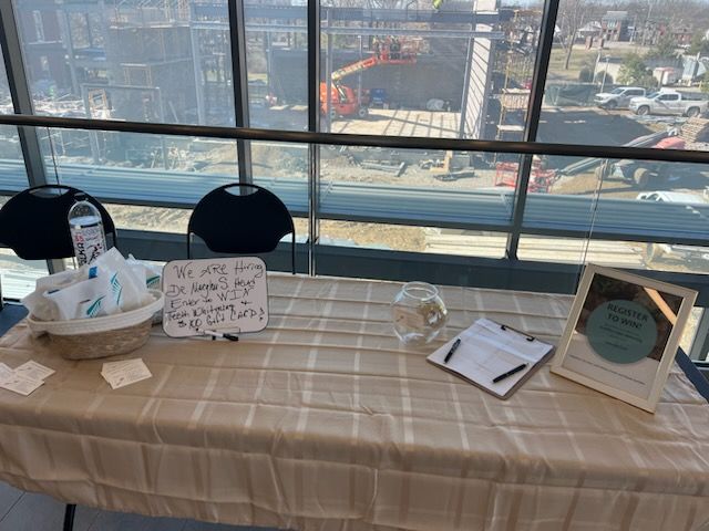 Display table with cards, books, and framed sign in front of large city-view windows