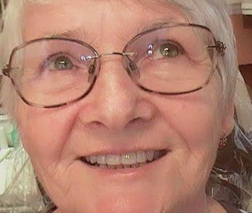Close-up of a smiling person wearing glasses in warm indoor light