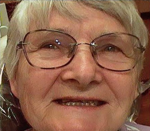 Close-up of an elderly woman wearing glasses, smiling softly.