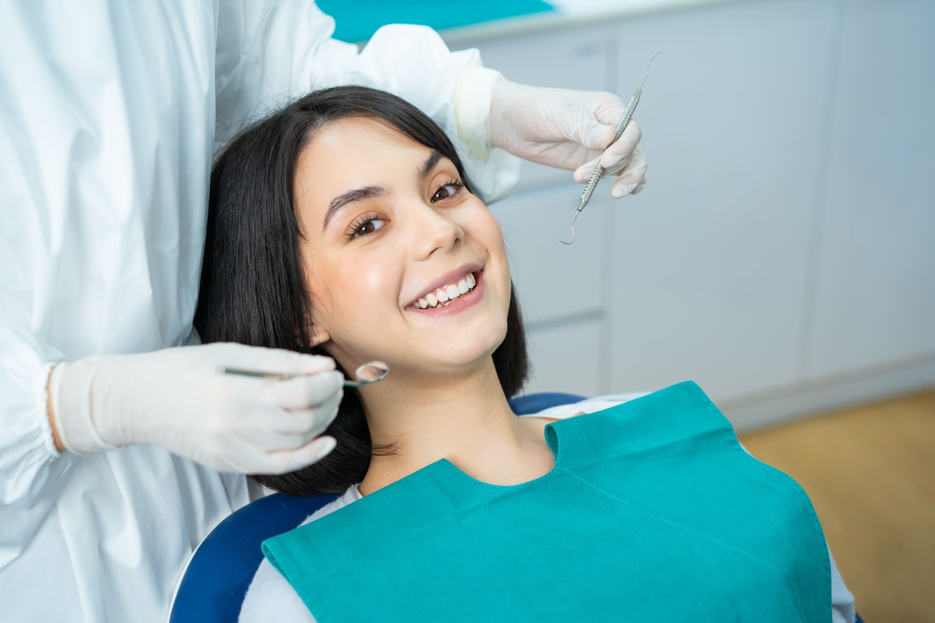 Dental patient smiling in a clinic while a dentist adjusts her teeth with gloved hands
