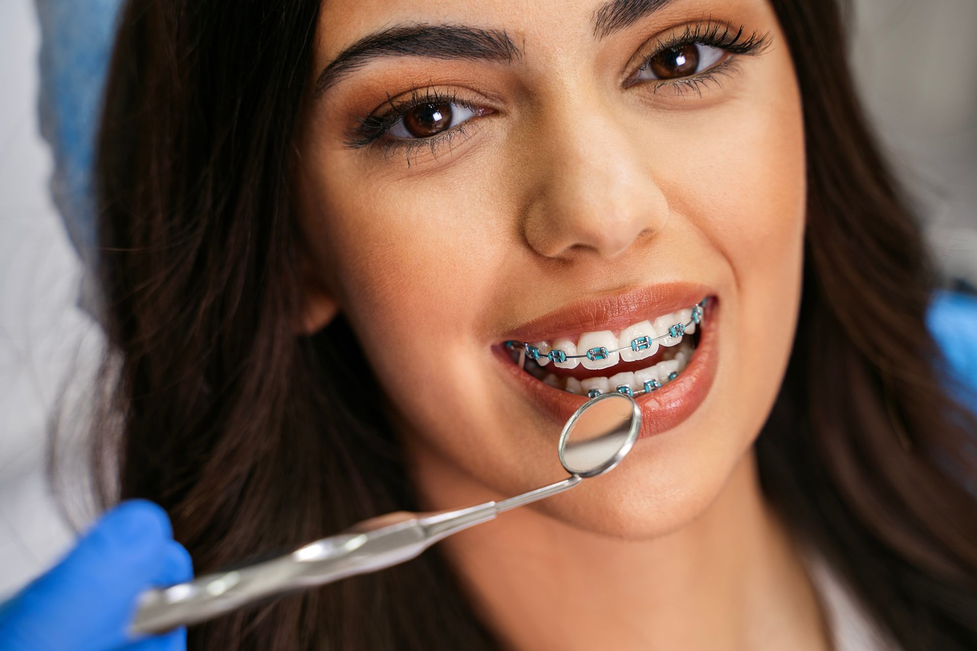Dentist examining a patient’s braces with a dental mirror and tool