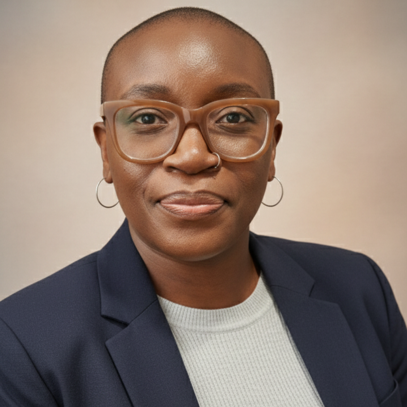 NURU Mo, with glasses and a blazer looking at the camera.