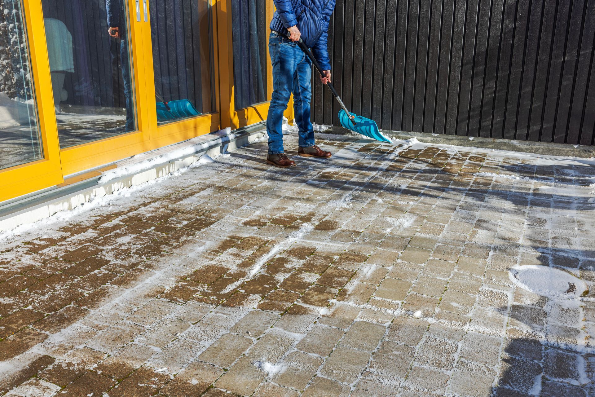A man is cleaning a patio with a broom.