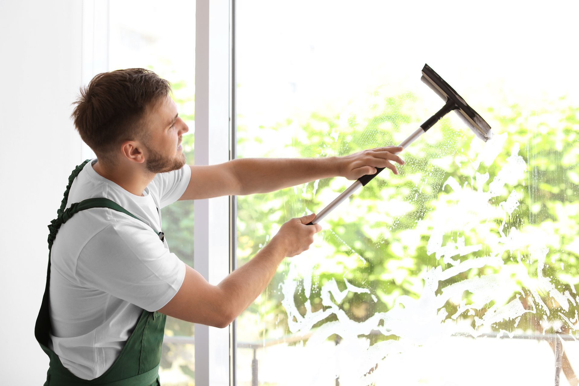 A man is cleaning a window with a squeegee.