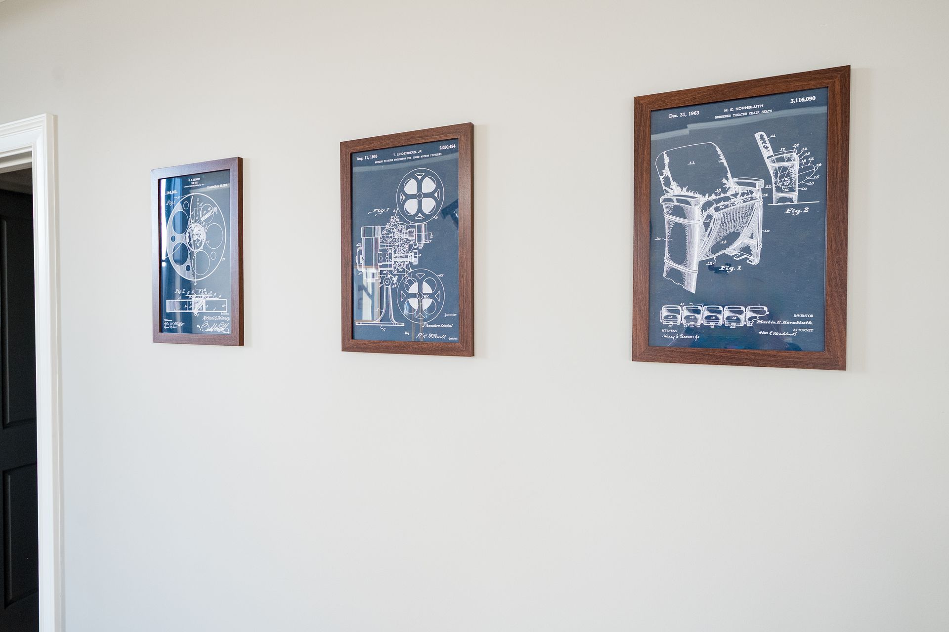Three framed blue-and-white technical prints on a white wall in a hallway