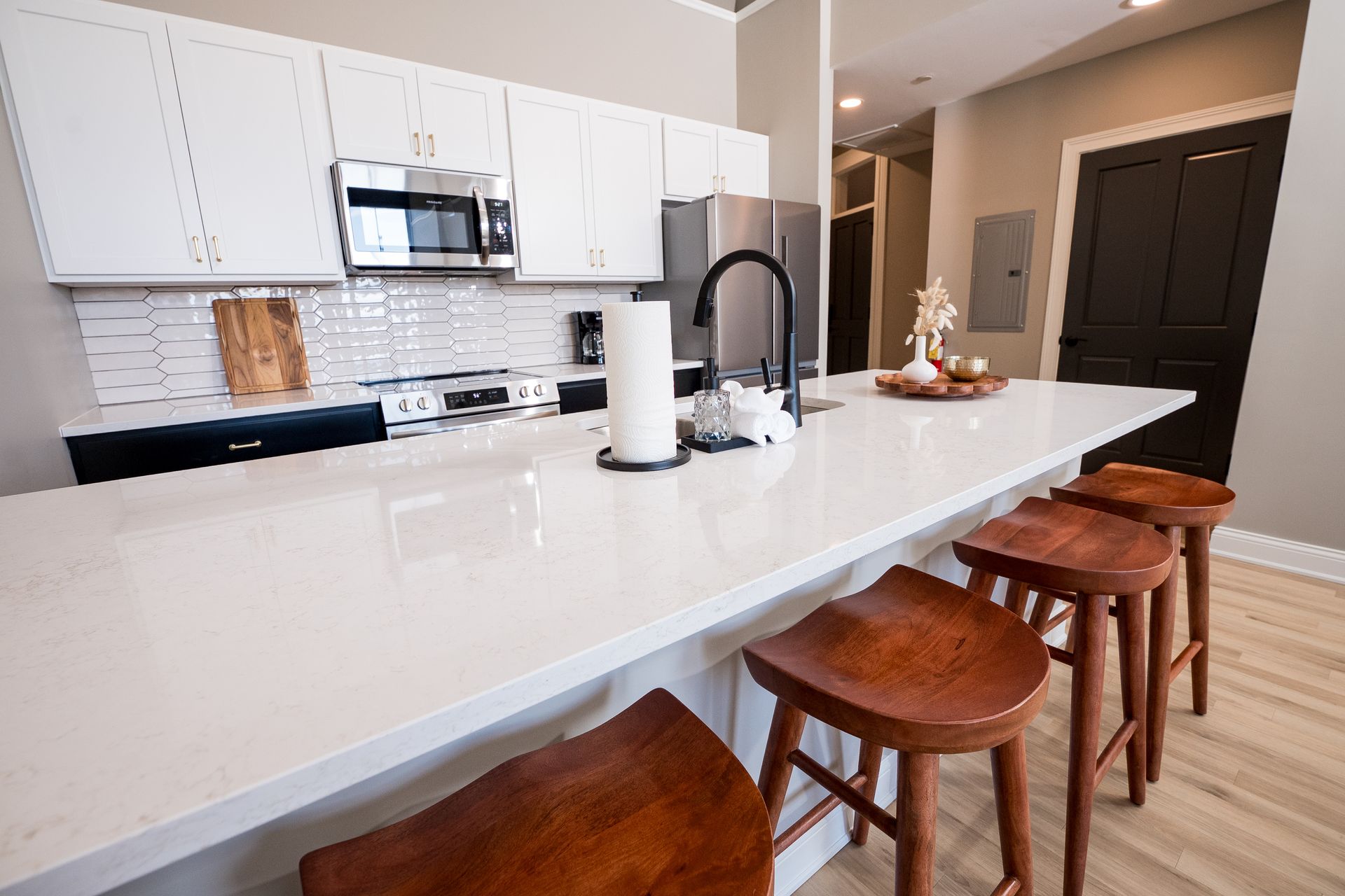 Modern kitchen with white island, brown stools, and stainless steel appliances