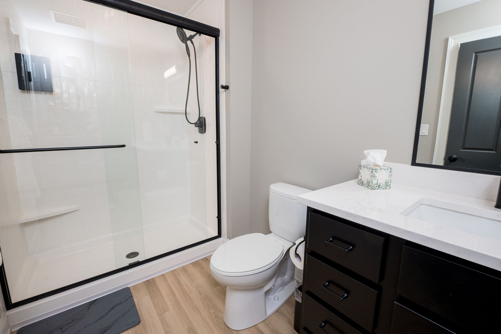 Modern bathroom with a glass shower, toilet, and dark vanity with sink.