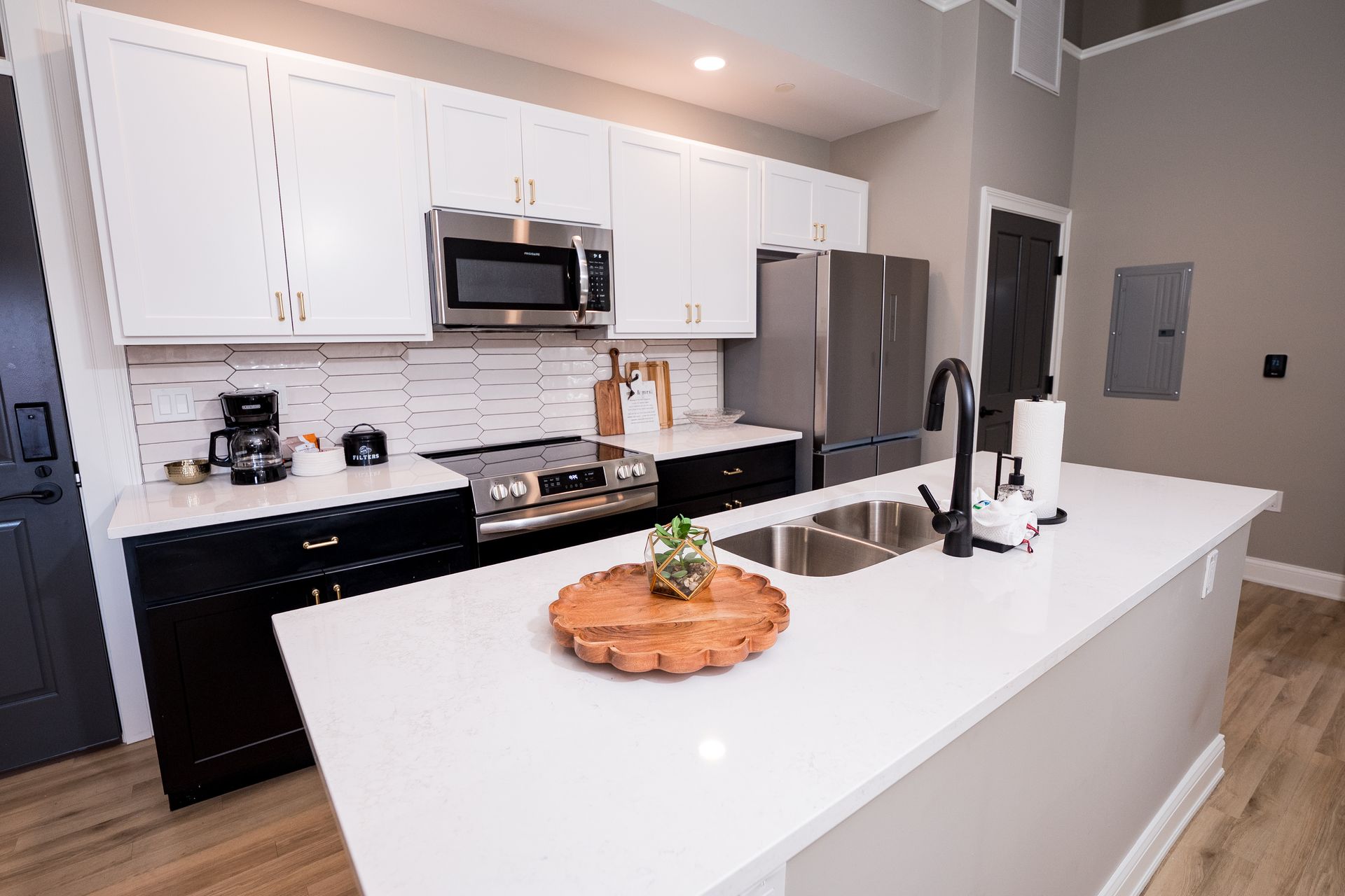 Modern kitchen with white cabinets, stainless appliances, and a large island with sink and fruit centerpiece