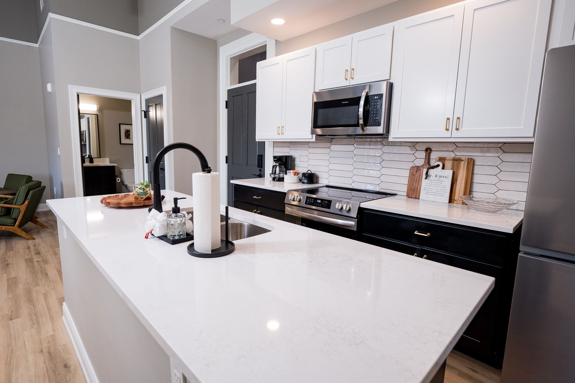 Bright modern kitchen with white cabinets, black appliances, and a large white island countertop