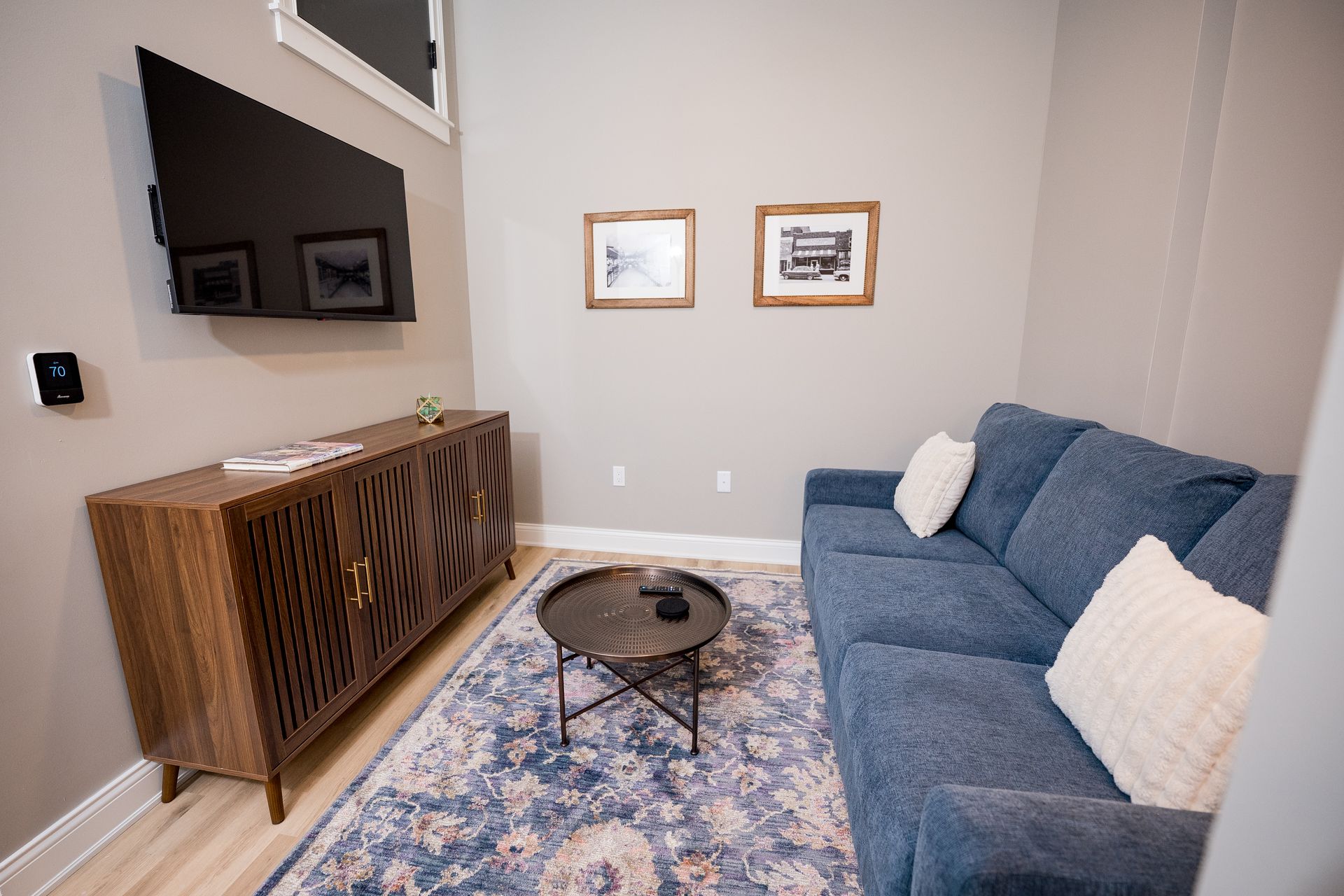 Cozy living room with blue sofa, patterned rug, coffee table, wood console, and framed wall art.