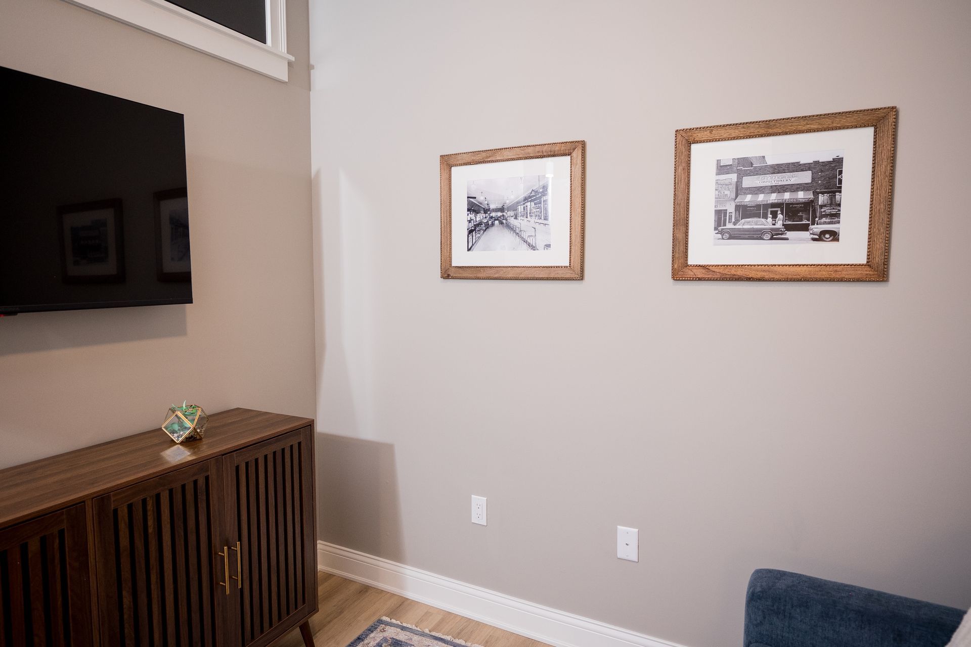 Living room wall with two framed black-and-white prints, a dark wood cabinet, and a TV on the left