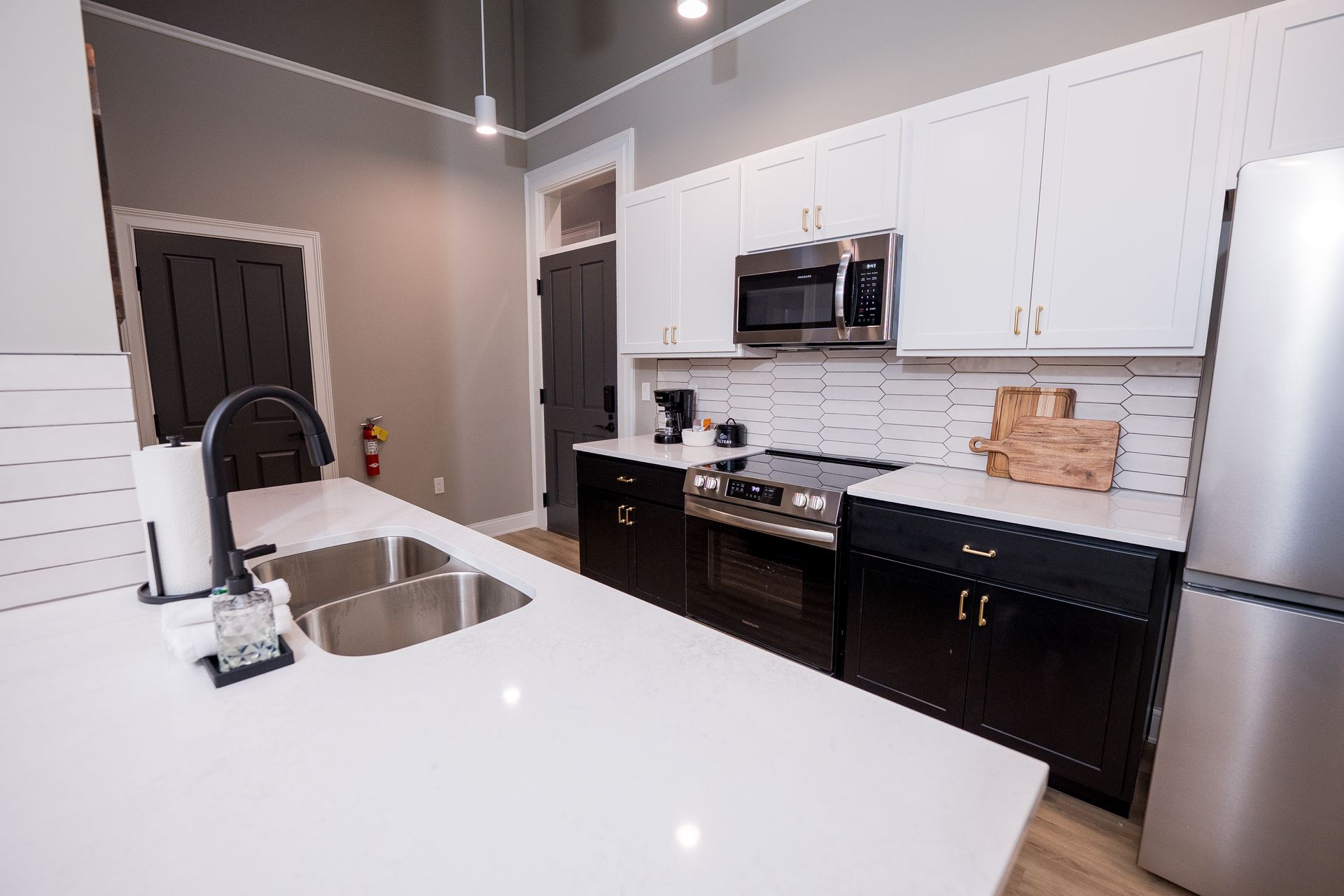 Modern kitchen with white island, black appliances, gray walls, and stainless steel sink.