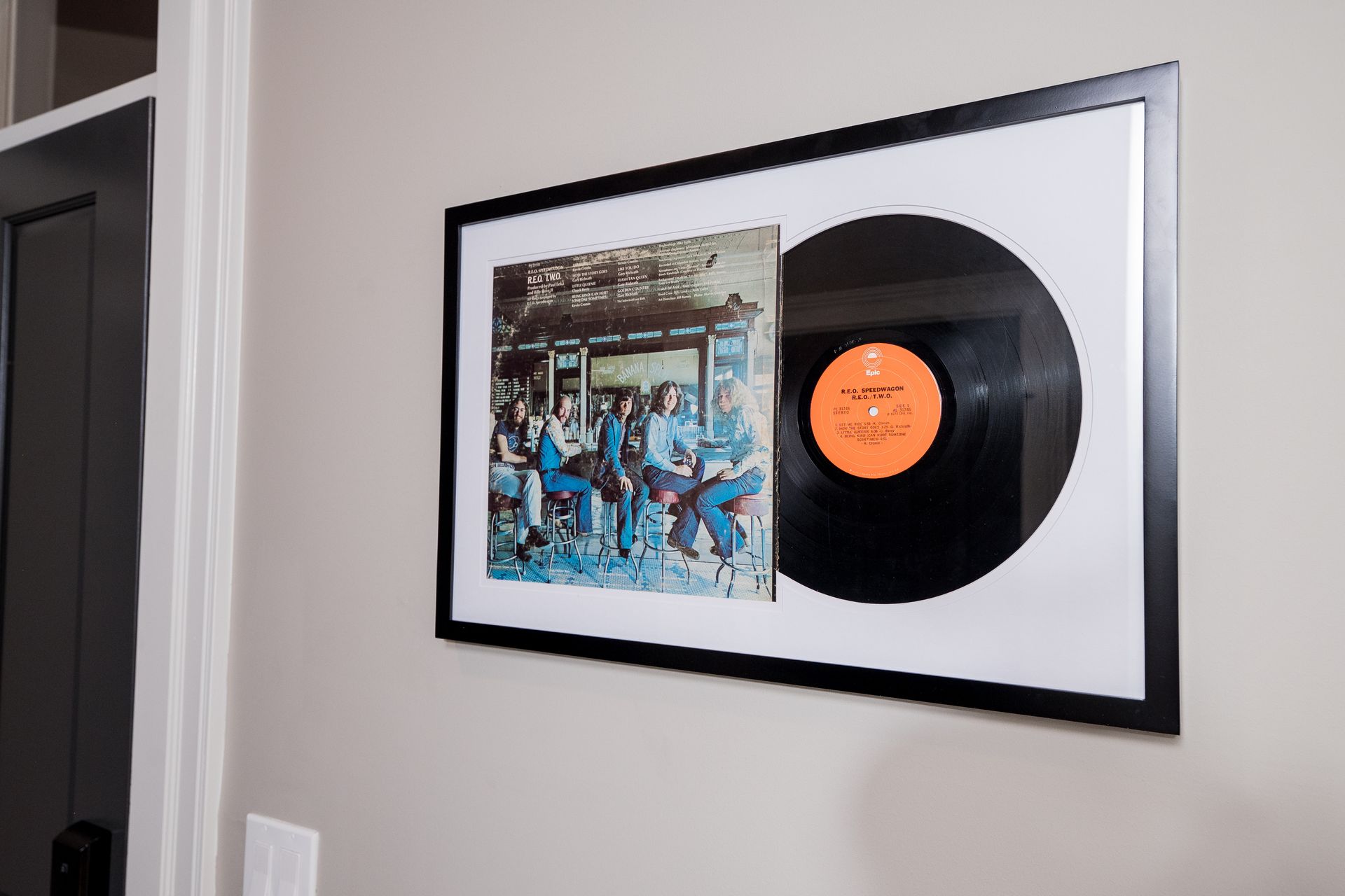 Framed vinyl record display on a wall with album art and black record with orange label
