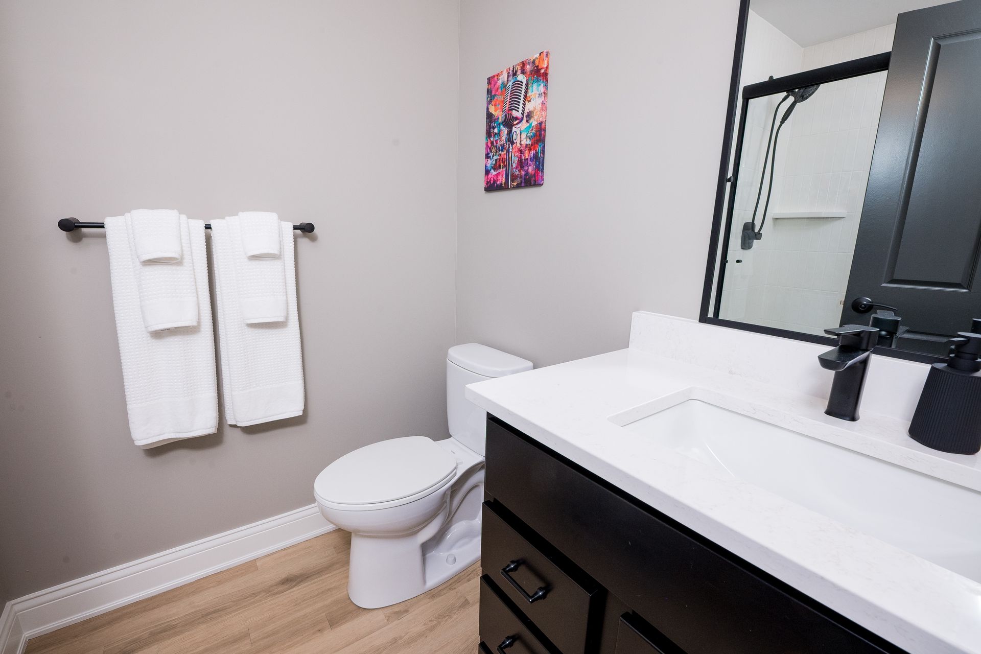 Modern bathroom with white towels, toilet, vanity sink, and black-framed mirror