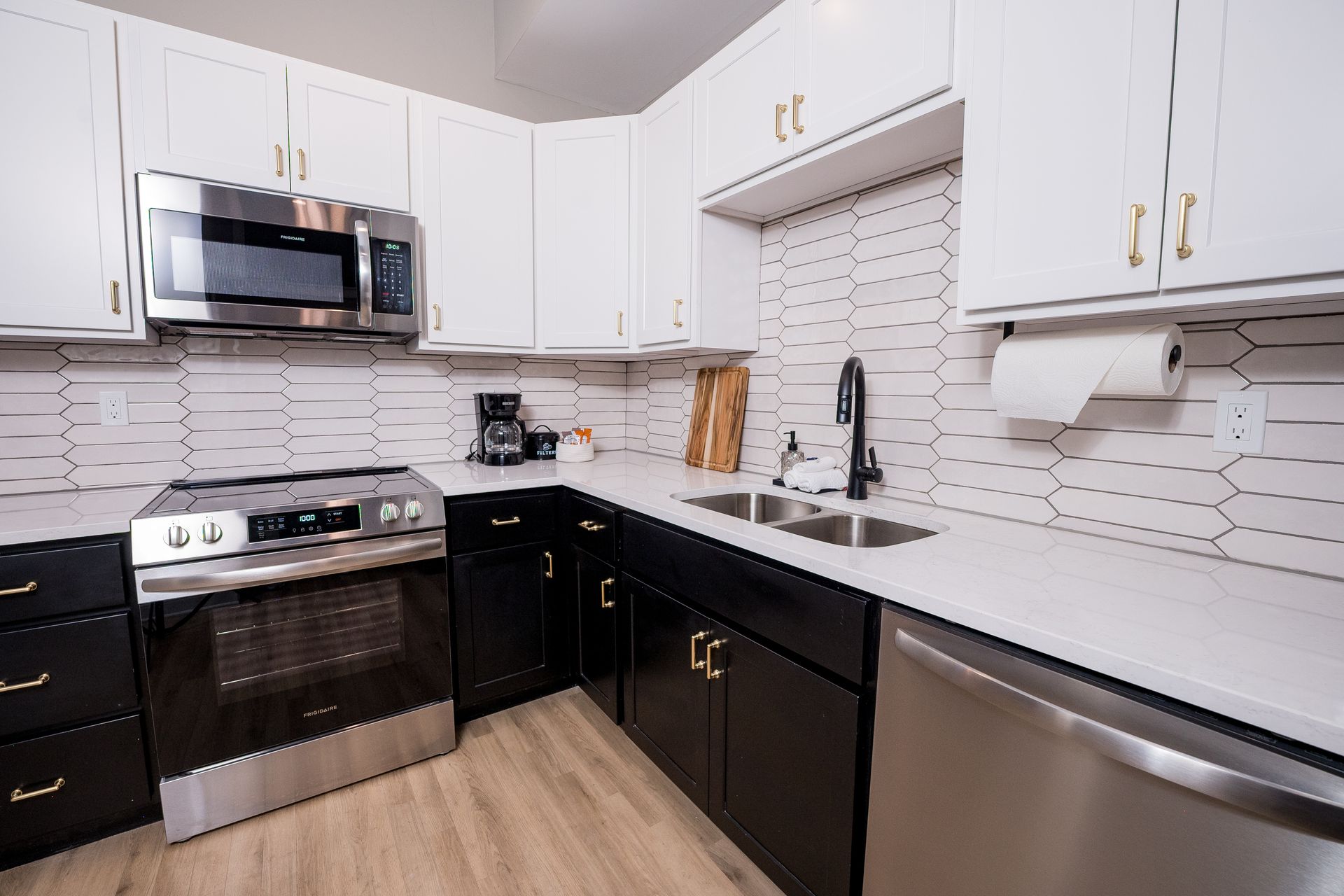 Modern kitchen with white cabinets, stainless steel appliances, black counters, and a tiled backsplash
