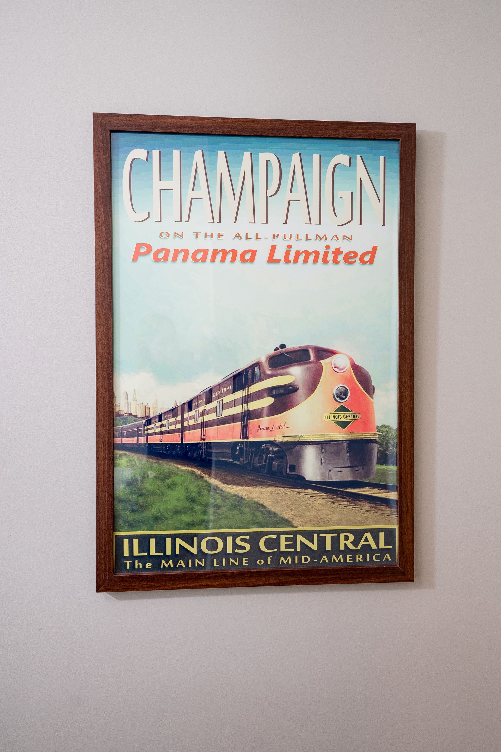 Vintage Chicago and Panama Limited Illinois Central train poster with a red locomotive on a wall