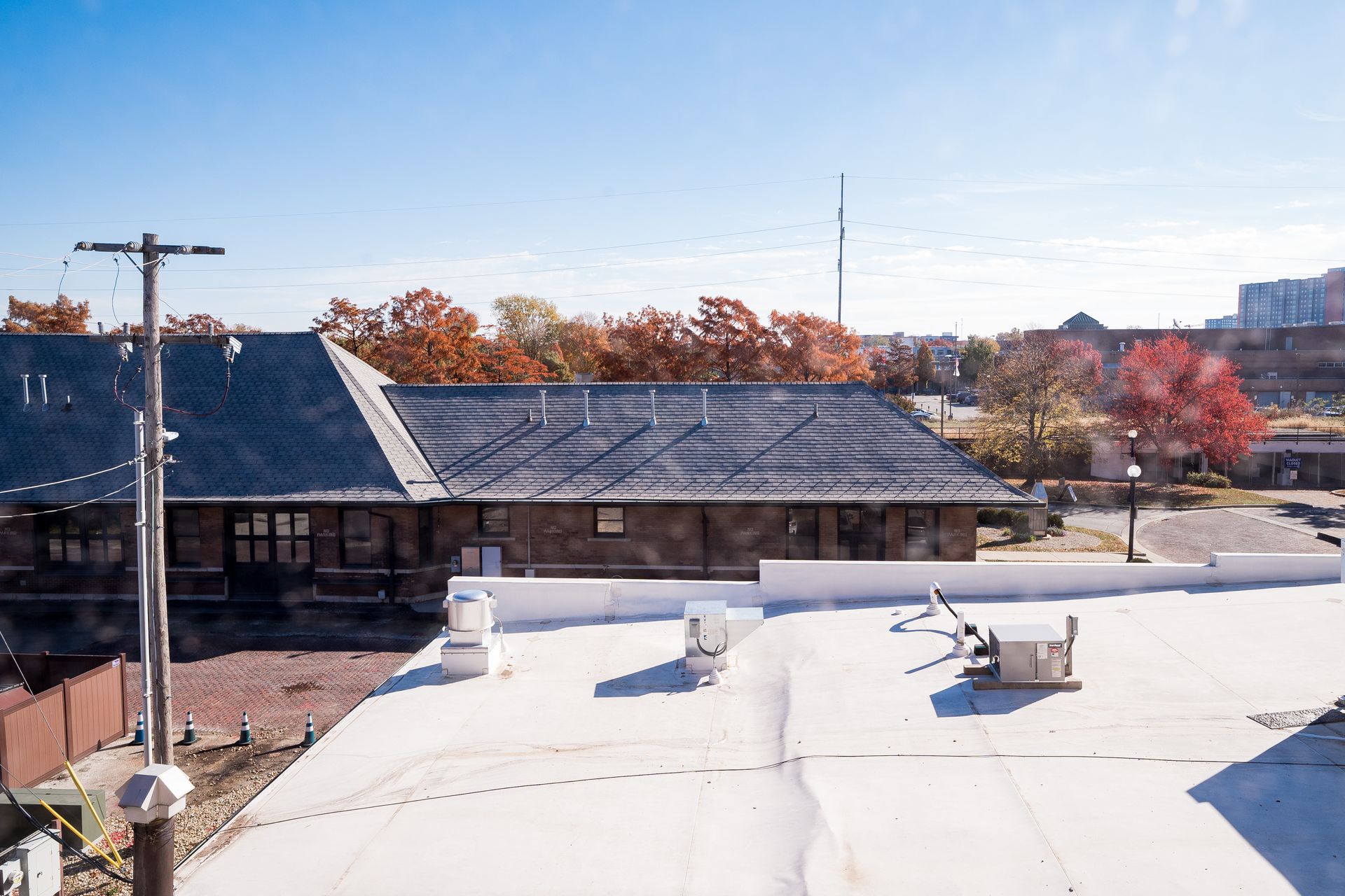 Rooftops with autumn trees under a clear blue sky, seen from above in a neighborhood scene