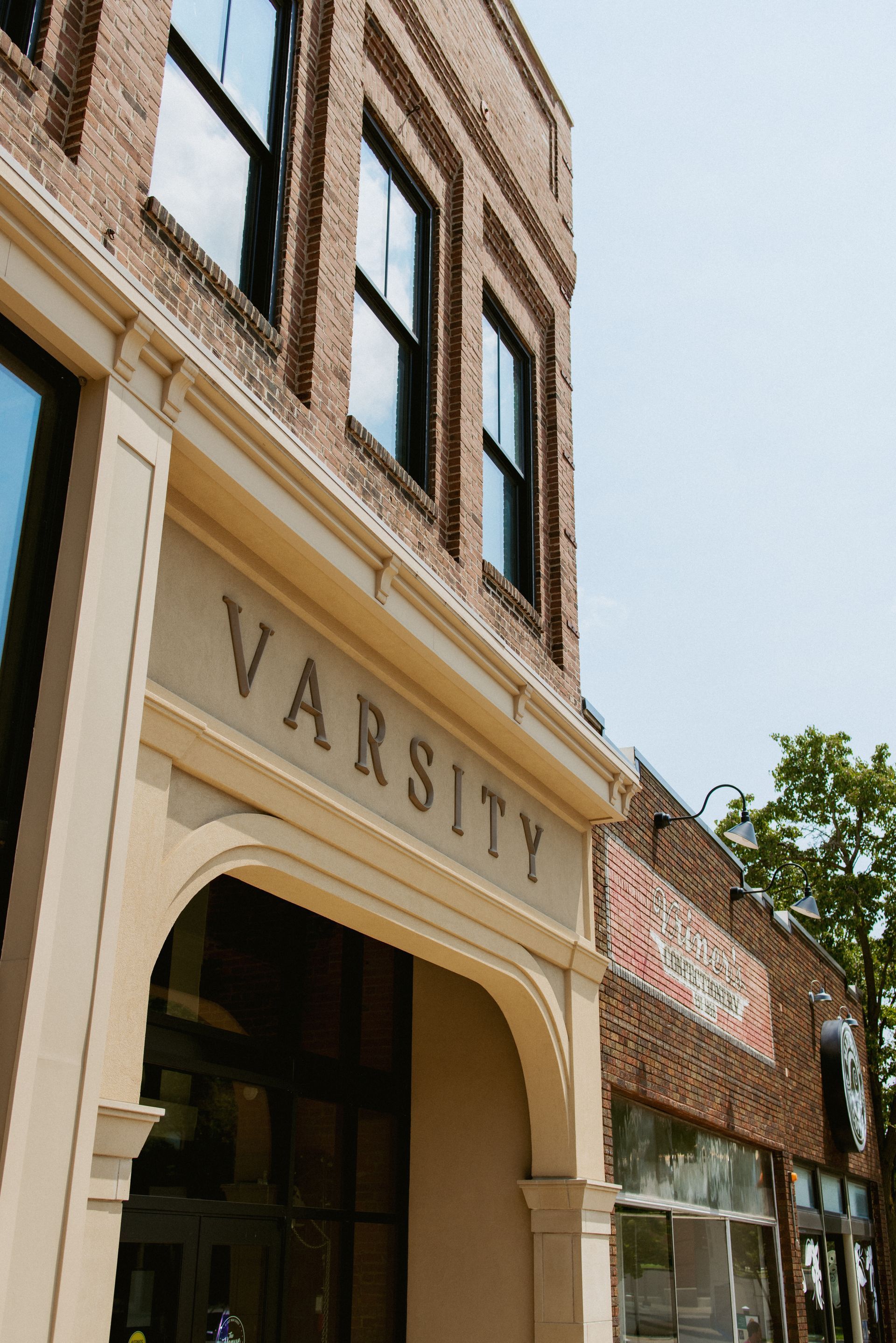 Historic brick storefront with arched entrance and “Varsity” sign above the door