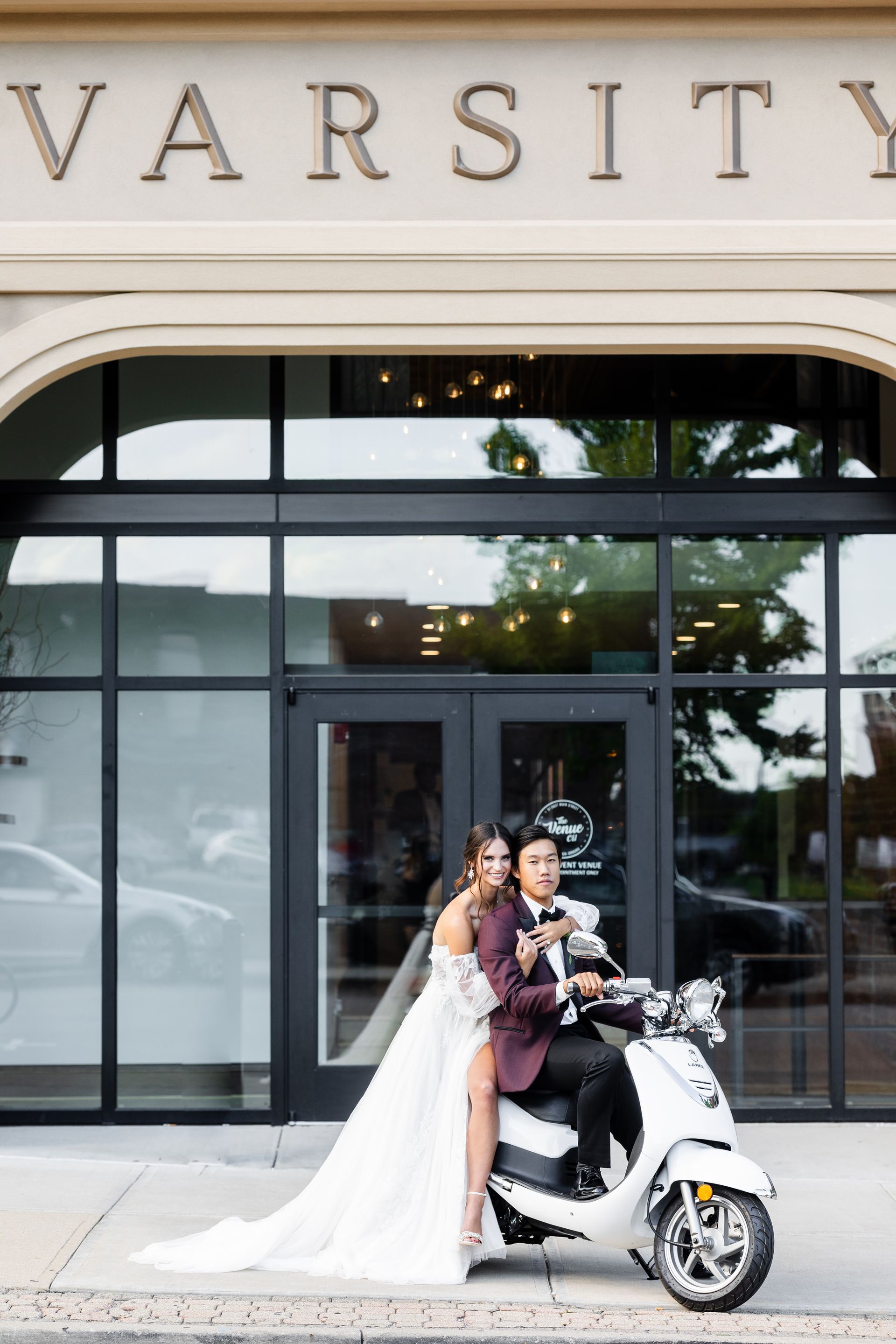 Bride and groom on a white scooter in front of a Varsity storefront