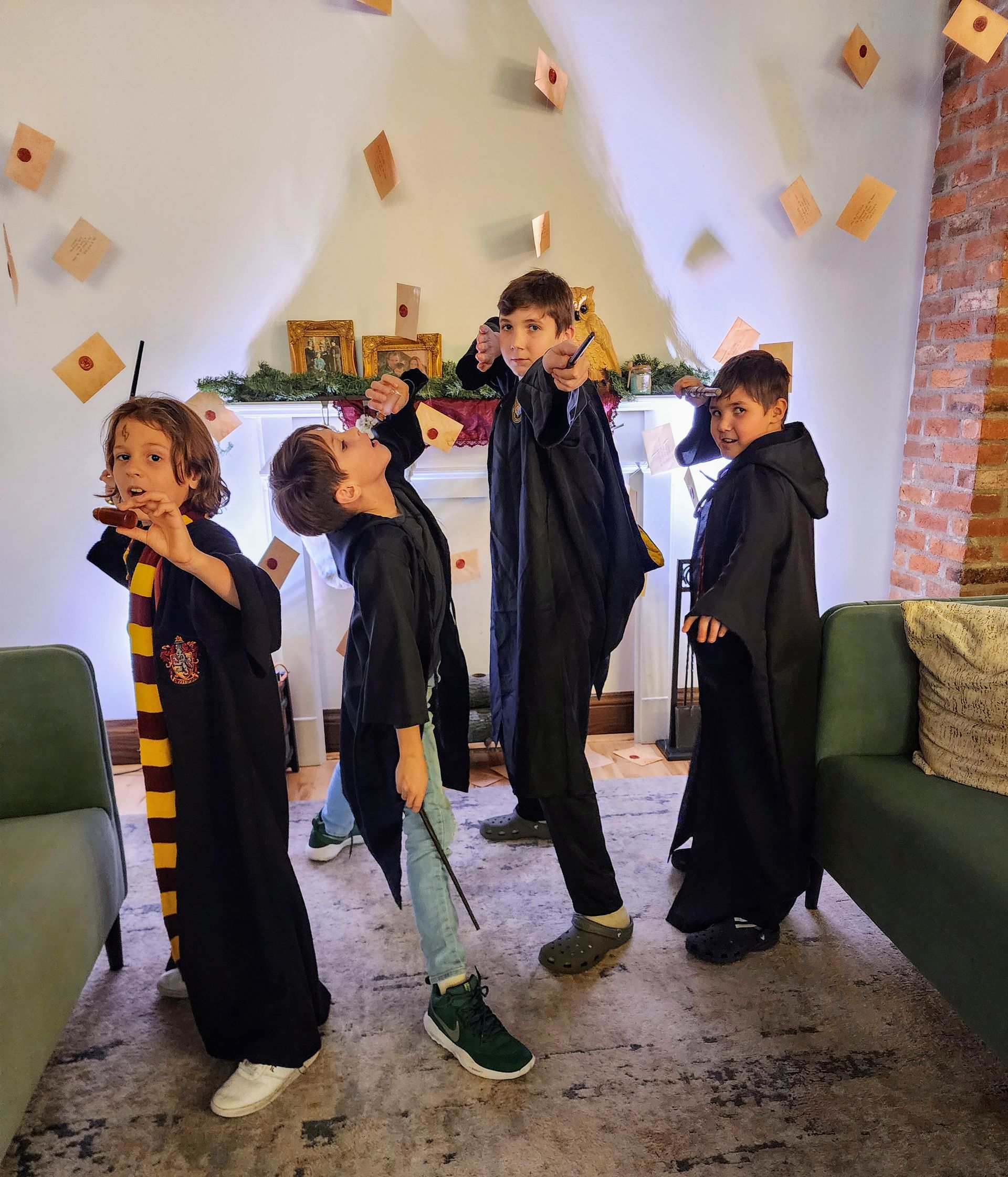 Four children in black costumes posing indoors with one holding a microphone-like prop.