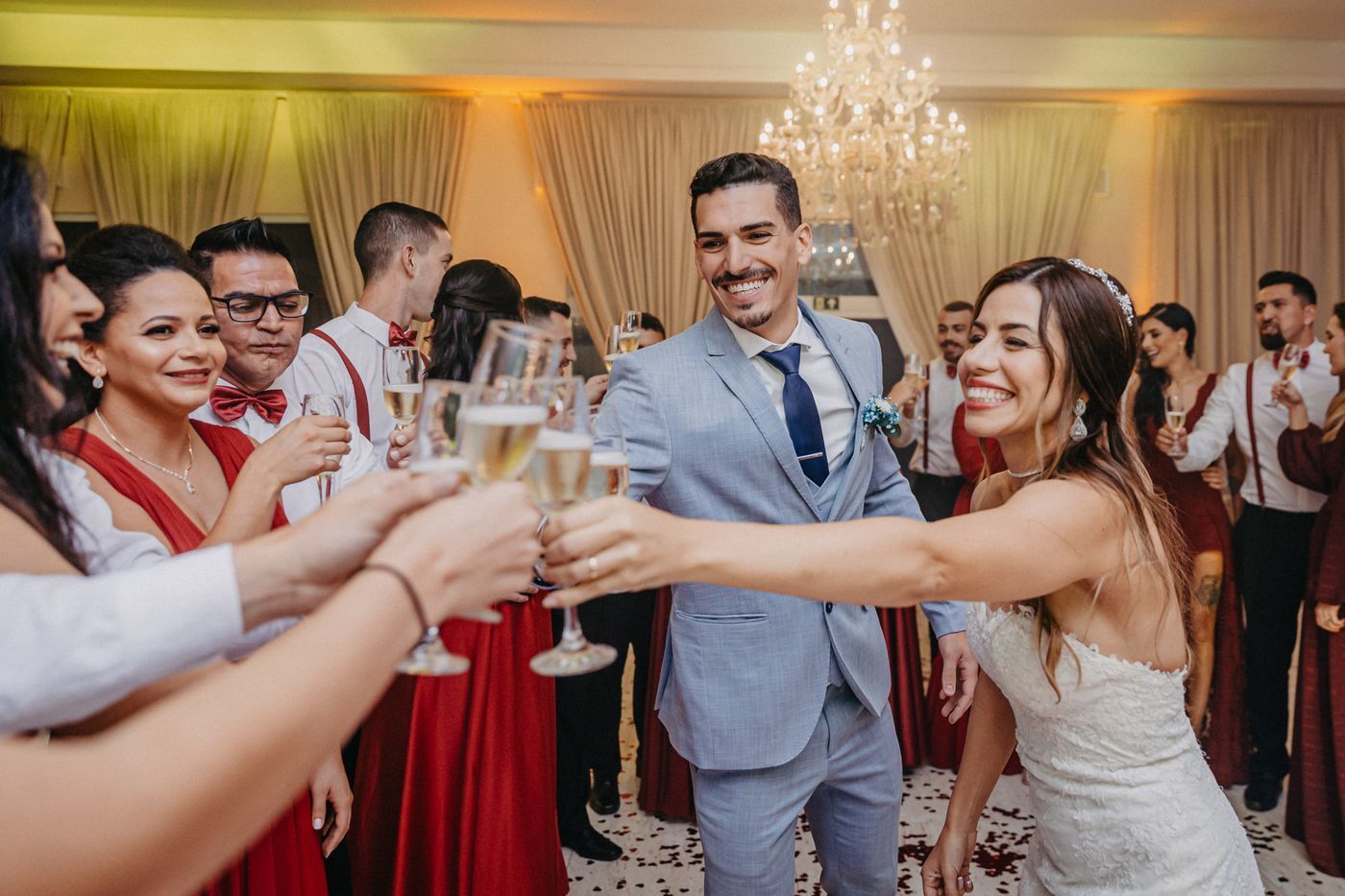 Wedding guests in formal attire raise champagne glasses in a celebratory toast indoors