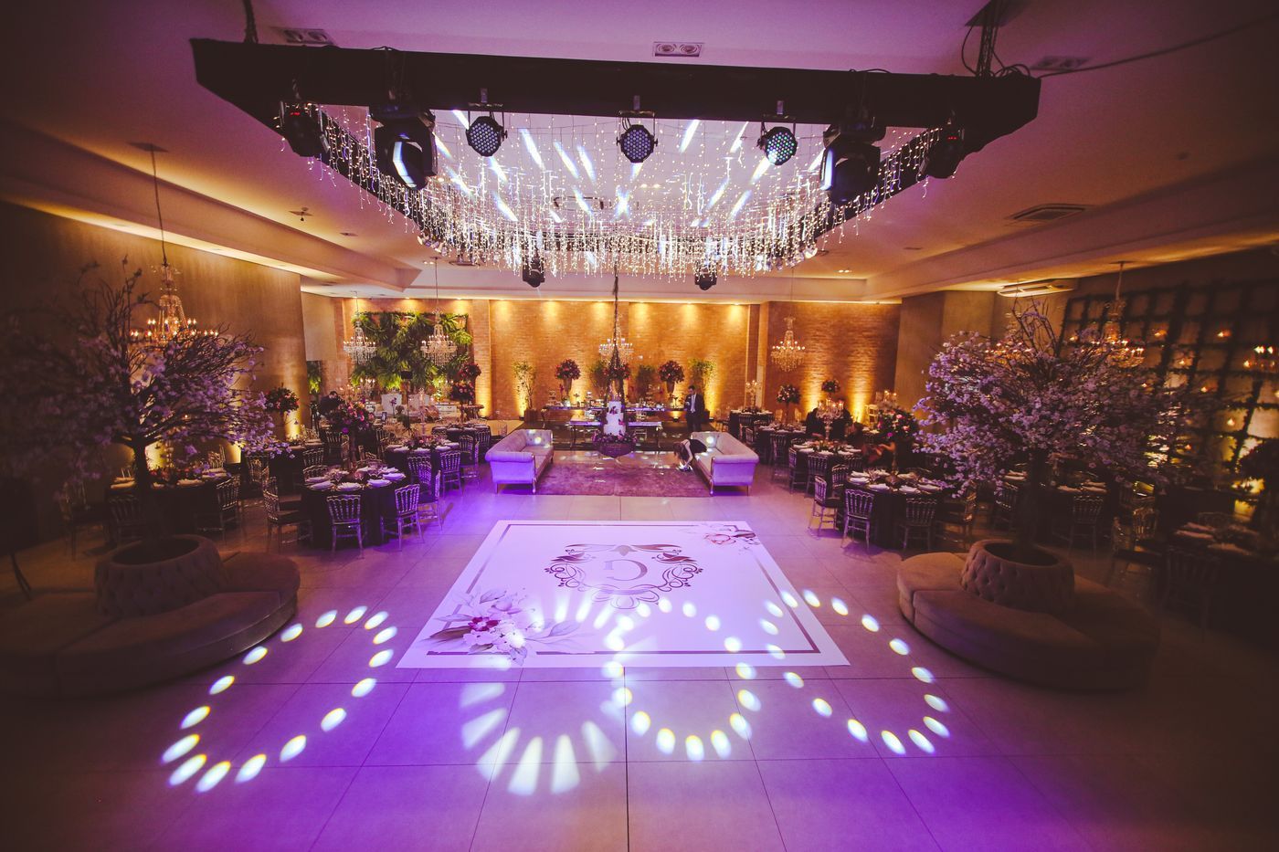 Elegant banquet hall with chandeliers, purple lighting, and a central dance floor