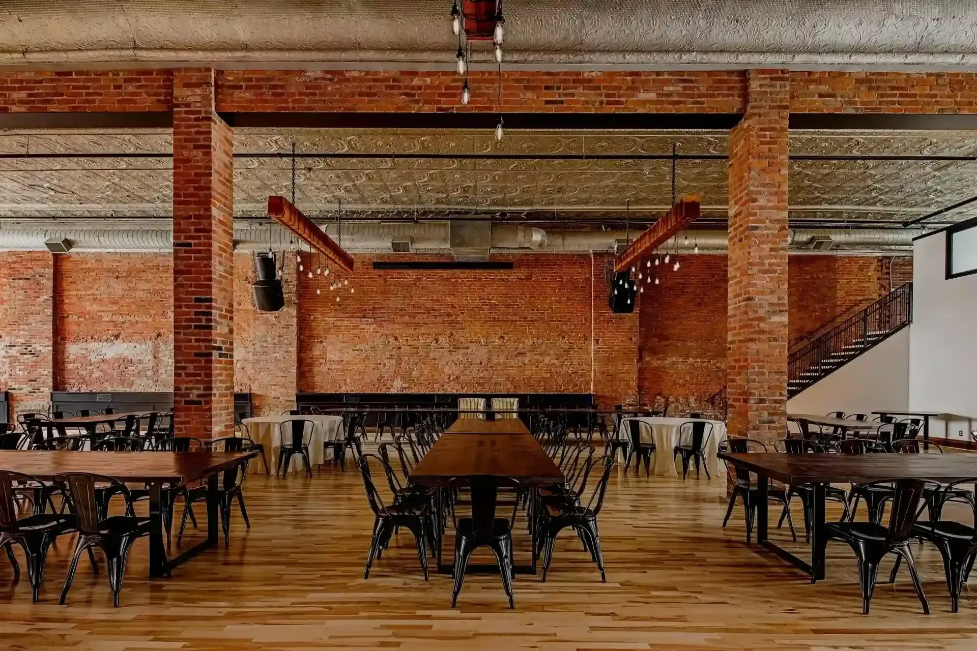 Empty rustic restaurant interior with brick walls, wooden tables, and metal chairs