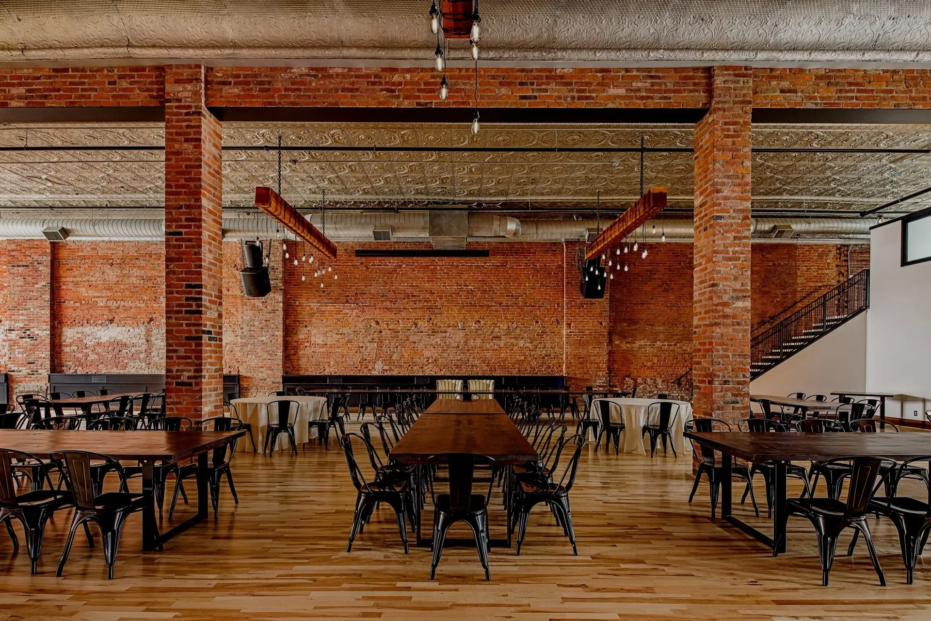 Empty rustic restaurant interior with brick walls, wooden tables, and metal chairs