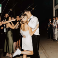 Couple kissing at a nighttime celebration, surrounded by cheering guests and sparklers