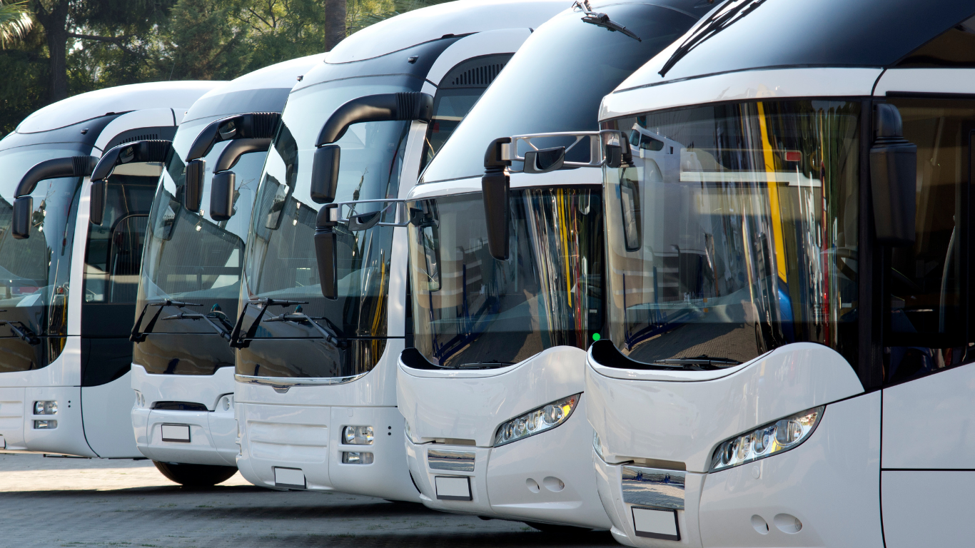 Row of white coaches parked side by side in a bus depot