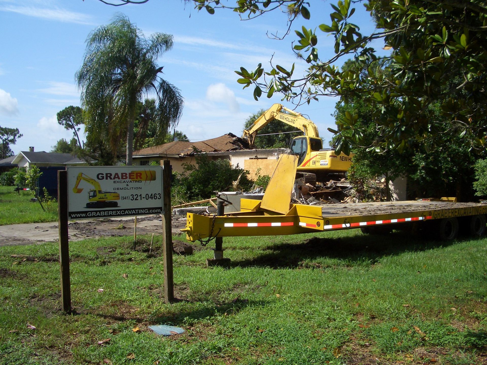 A large orange excavator is demolishing a building.