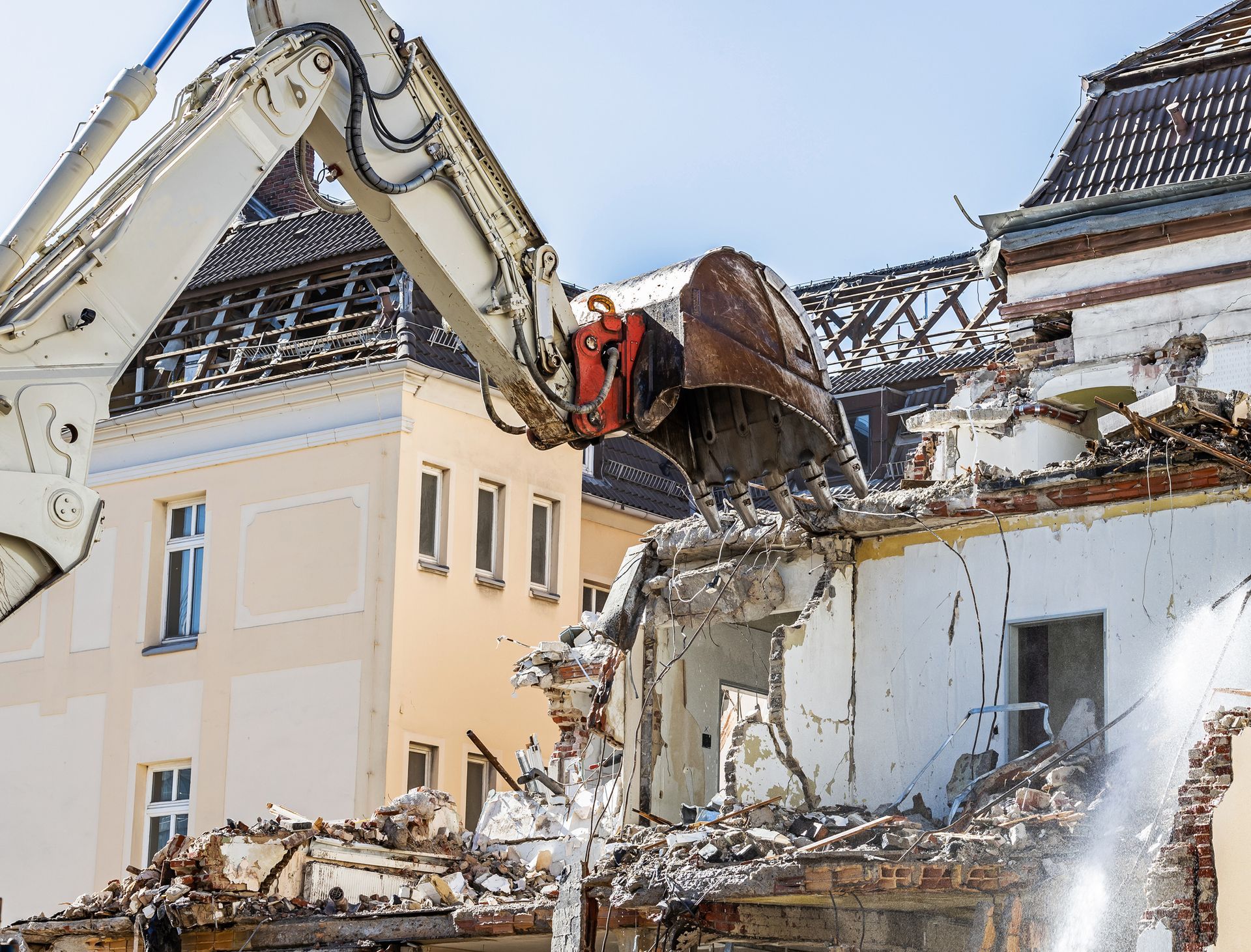 A large white excavator is demolishing a building.