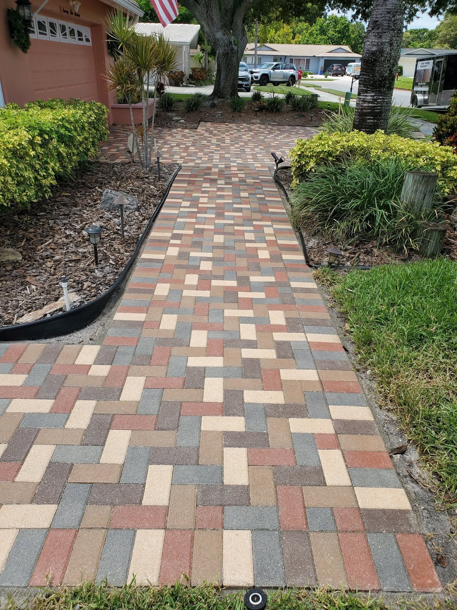 Colorful brick walkway leading through landscaped greenery toward a building entrance