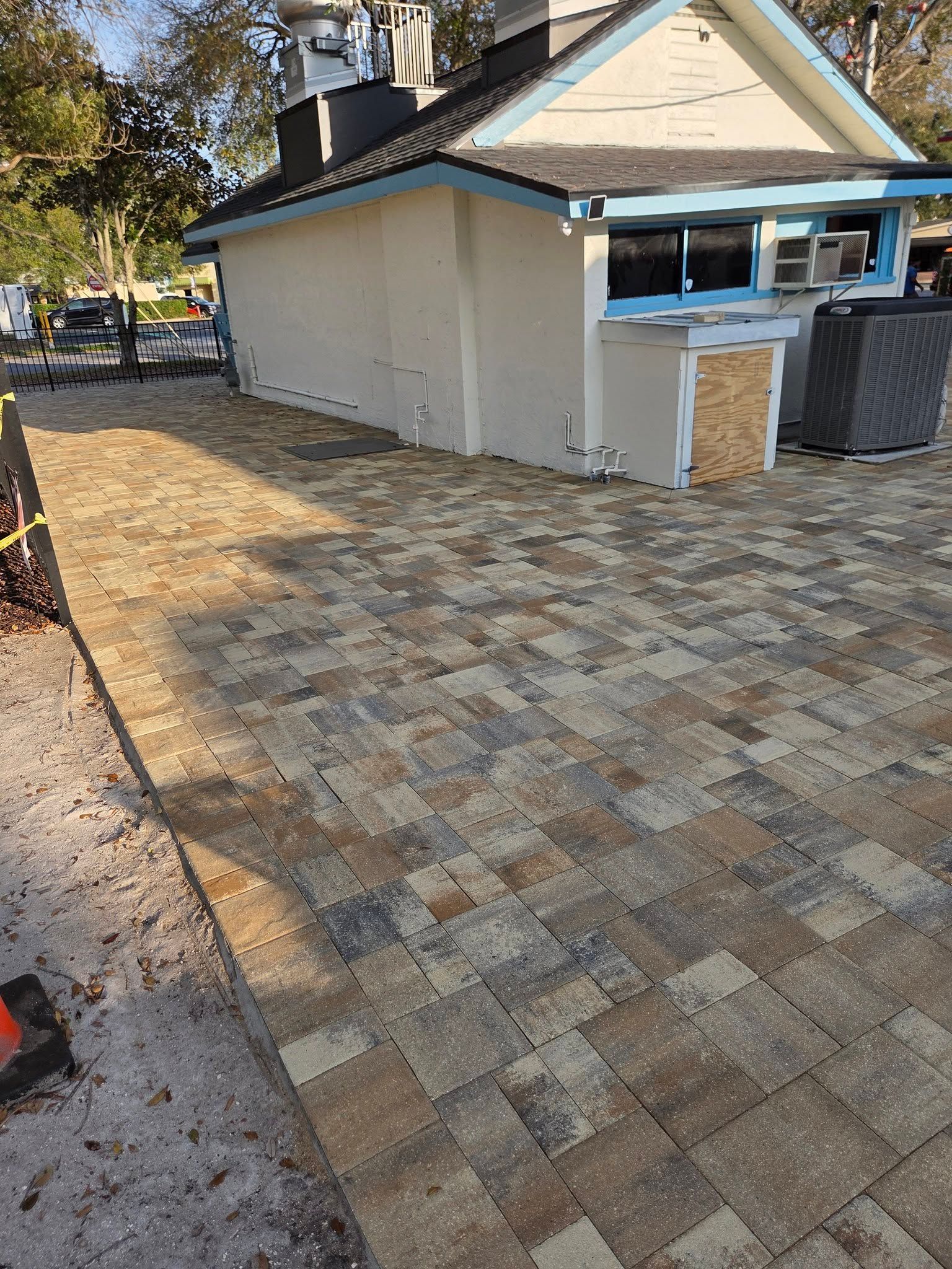 Brick-paved patio beside a beige house with a small outdoor bar and covered grill area