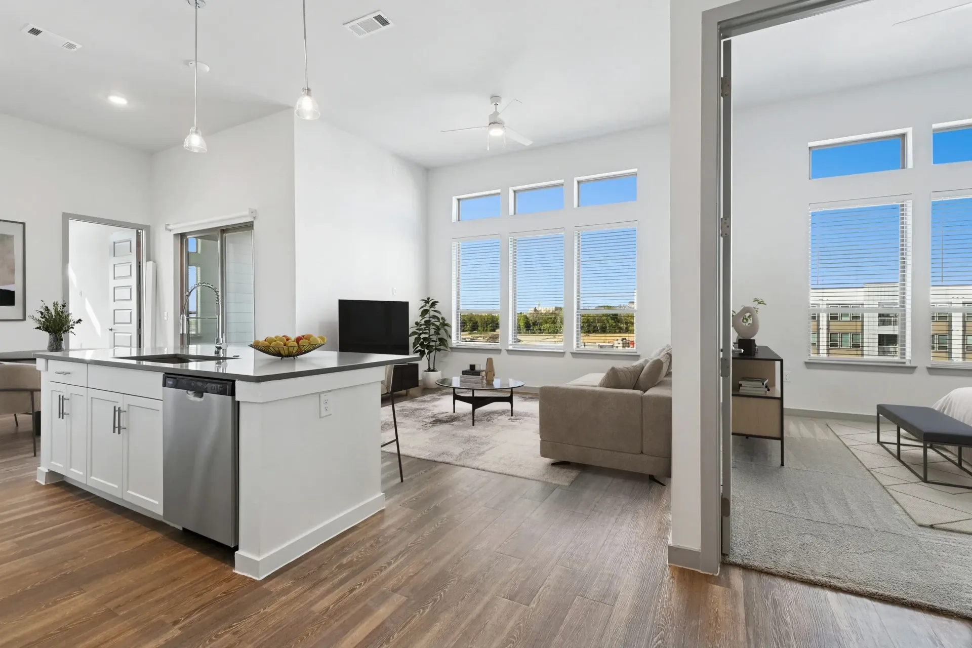Bright open-concept kitchen and living area with white cabinets, island, and large windows at Ennova Highlands apartments in Arlington, TX.