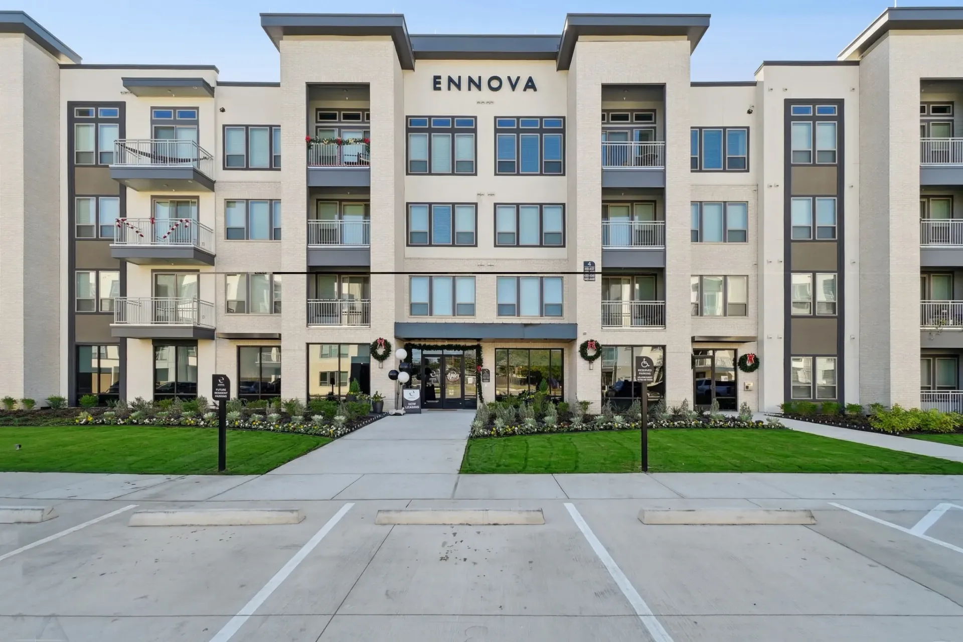 Exterior view of ENNOVA apartment building with balconies and landscaped entrance at Ennova Highlands apartments in Arlington, TX.
